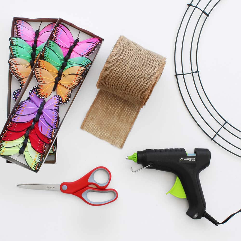 disposición plana de mariposas de papel, cinta de yute natural y pistola de pegamento caliente