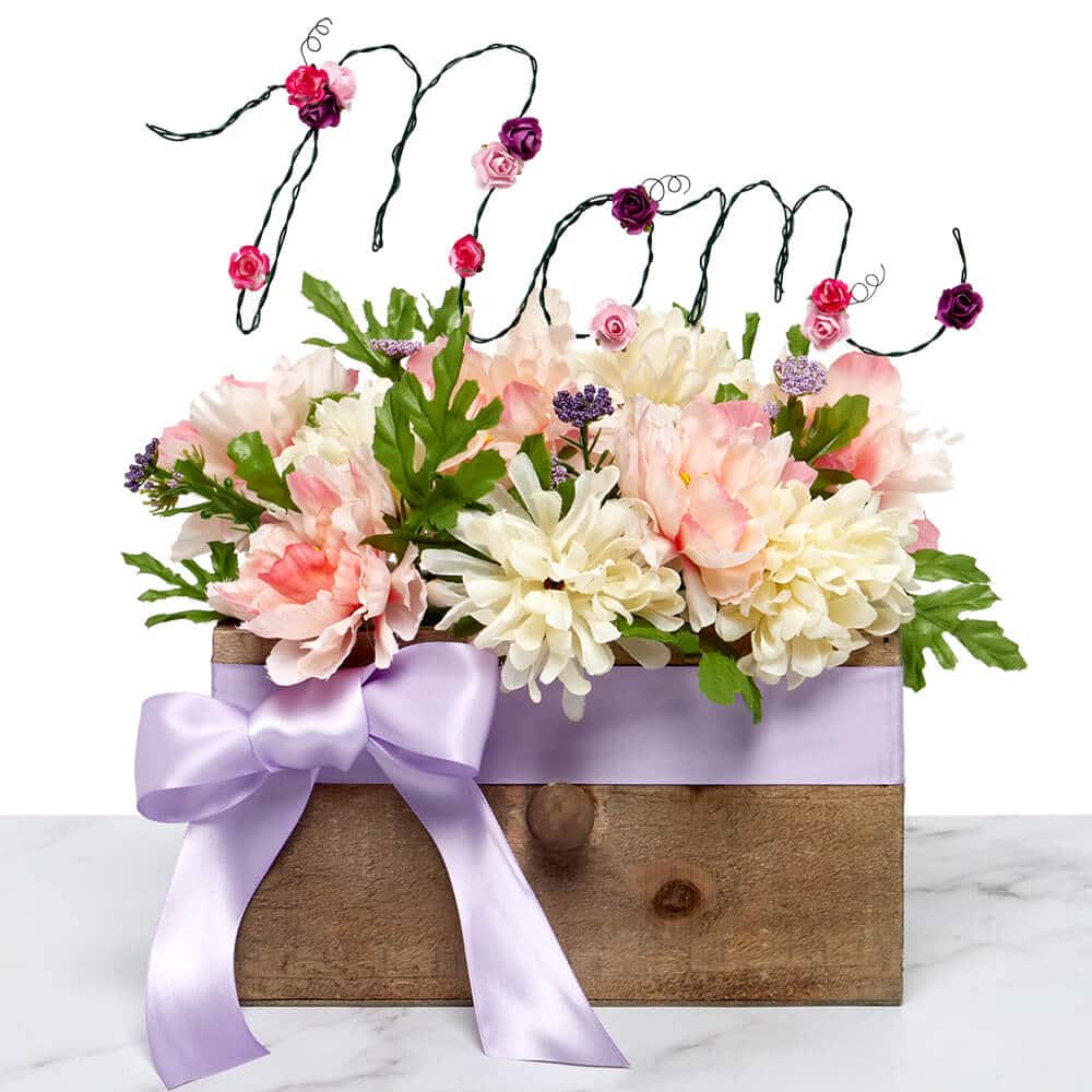 ramo de flores en un recipiente de madera acentuado por una cinta de raso del mercado del papel y "mamá" etiqueta de jardín